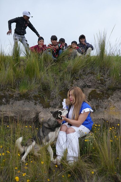 Enissa sitzt in den Hochanden mit einem Hund. 