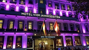 Das Hotel Vier Jahreszeiten ist im Dunkeln anlässlich des Weltmädchentages pink beleuchtet. 