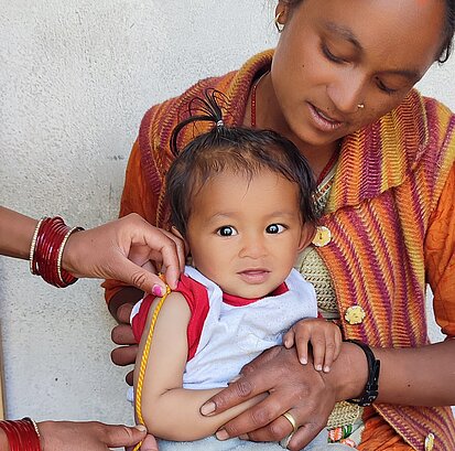 Eine Frau misst den Arm eines Kleinkindes