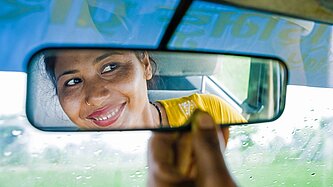 Eine junge Frau blickt in den Rückspiegel