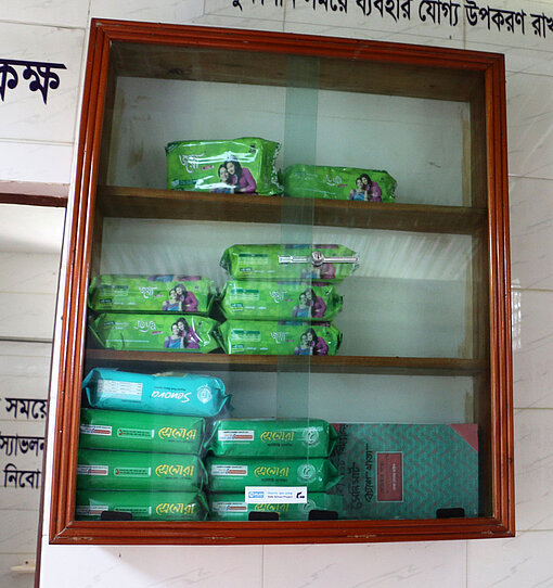 Der Sanimart ist ein Schrank, aus dem Schüler:innen sich Menstruationsprodukte besorgen können. Ein Wandschrank mit Glastür, in dem Menstruationsprodukte liegen.