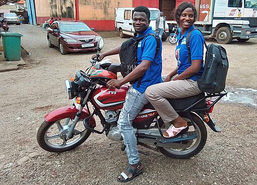 Auf einem der Motorräder in der guineischen Hauptstadt Conakry sitzt das medizinische Team von Plan International Ein Paar auf einem Motorrad
