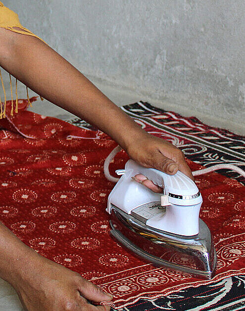 Jede Ecke eines Bekleidungsstücks muss bei Aarati (20) sitzen und knitterfrei sein Hände einer Frau mit Bügeleisen