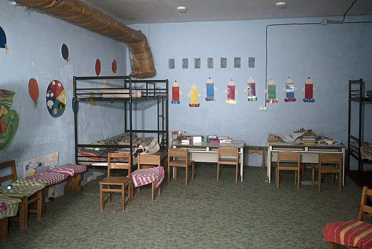 In einem Raum ohne Fenster stehen Stühle und Tische für Kinder.