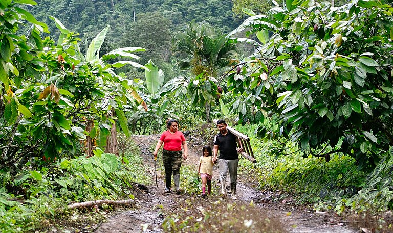 Yenny steht gemeinsam mit ihrem Mann und ihrer jüngsten Tochter in einer ländlichen Gemeinde in Ecuador.
