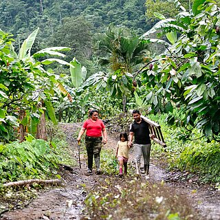 Yenny steht gemeinsam mit ihrem Mann und ihrer jüngsten Tochter in einer ländlichen Gemeinde in Ecuador.