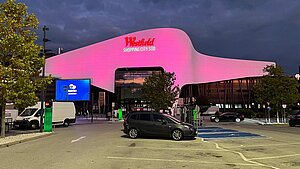 Das "Westfield Shopping-Center Süd"-Gebäude wird im Dunkeln in Pink beleuchtet.