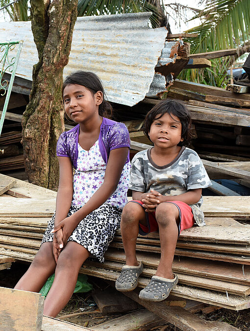 Hurrikan Iota hat in Nicaragua Spuren der Verwüstung hinterlassen. Zwei Kinder sitzen auf Holzbalken vor einem kaputten Haus.