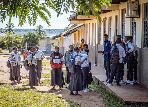 Den Bau der Schule in dieser ländlichen Region von Inhambane hat Plan International initiiert Jugendliche vor einem Schulgebäude