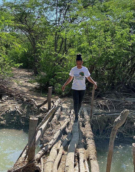 Junge Frau auf einer Holzbrücke über hellblauem Wasser