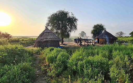 Plan International erreicht mit seiner humanitären Hilfe auch abgelegene Dorfgemeinschaften im nördlichen Upper Nile State Dorf mit Strohhütten im Sonnenuntergang