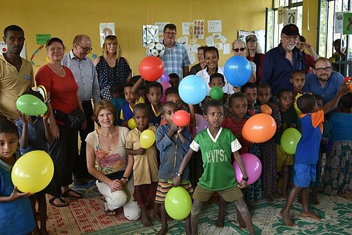 Pat:innen und Schulklasse mit Luftballons.