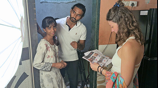 Ein Mädchen steht mit einer jungen Frau und einem jungen Mann in einem Raum zwischen Scheinwerferlicht und Videokamera am Filmset in Mumbai