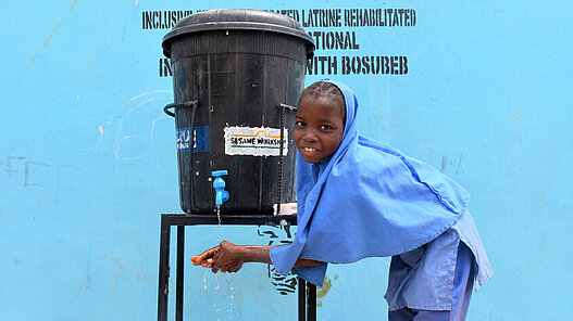 Ein Mädchen nutzt eine neue Handwaschstation von Plan International. 