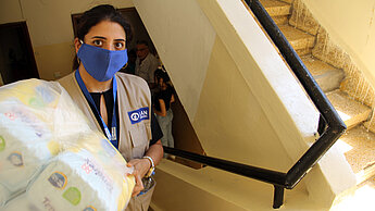 Es fehlt am Nötigsten: Eine Plan-Mitarbeiterin verteilt Klopapier in einem Wohnhaus. ©Plan International