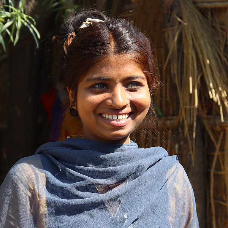 Poonam trägt ein blaues Gewand und strahlt.