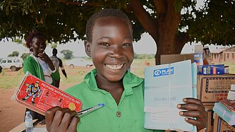 Eine Schülerin hält stolz ihre neuen Lernmaterialien in die Kamera