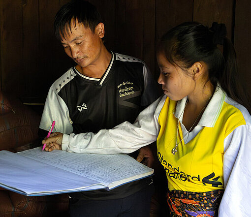 Zwei Menschen notieren Daten in ein großes Buch, das als Register für die Reisbank dient