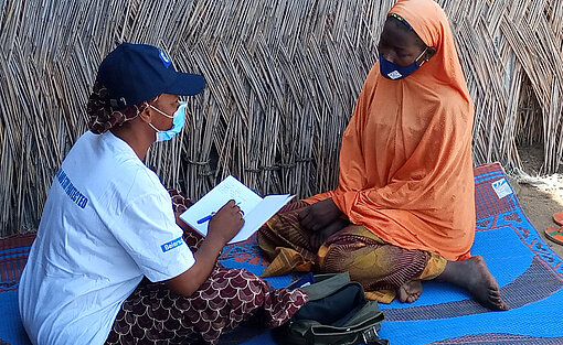 Eine Projektteilnehmerin in Nigeria mit ihrer Mentorin im Gespräch. Eine Frau sitzt mit ihrer Mentorin auf einer Matte und ist ins Gespräch vertieft.