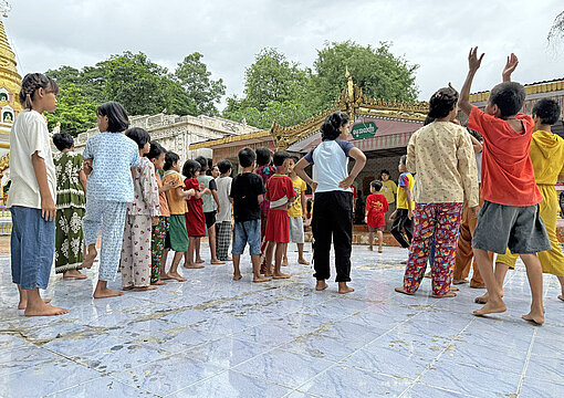 Mädchen und Jungen spielen auf dem Gelände eines buddhistischen Tempels
