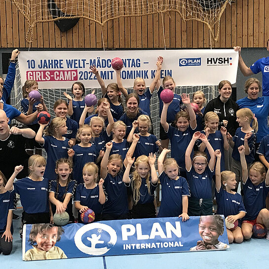 Eine große Gruppe Mädchen in Handball Trikots steht vor einem Tor zum Gruppenfoto zusammen. 