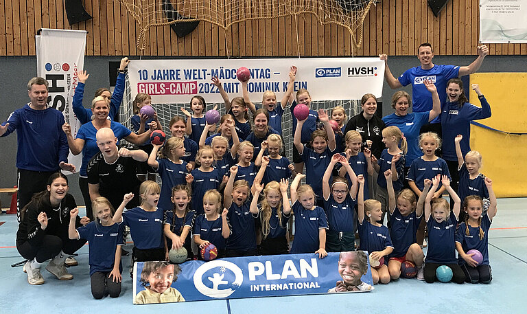 Eine große Gruppe Mädchen in Handball Trikots steht vor einem Tor zum Gruppenfoto zusammen. 