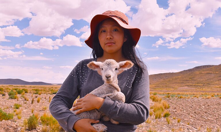 Eine Jugendliche hält ein Lamm im Arm