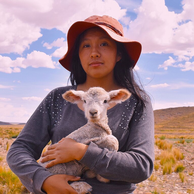 Eine Jugendliche hält ein Lamm im Arm