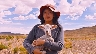 Eine Jugendliche hält ein Lamm im Arm