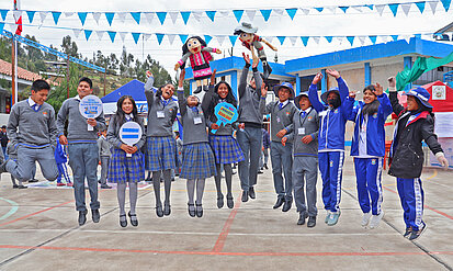 Jugendliche springen mit Schildern und Puppen in der Hand in die Luft