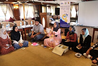 Eine Gruppe von Menschen hört einer Frau zu, die etwas erklärt