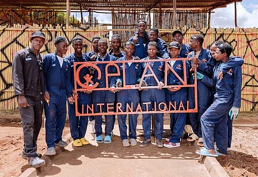 Auszubildende Schweißer:innen zeigen ihr aus Metall gemachtes Plan-Logo 