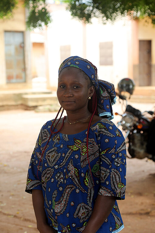 Porträt einer jungen, Schwarzen Frau mit Haarband und blauem, traditionell gemusterten Oberteil