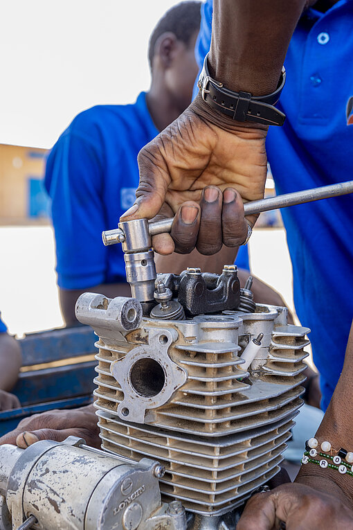 Nahaufnahme einer Hand, die an einem ausgebauten Motor schraubt