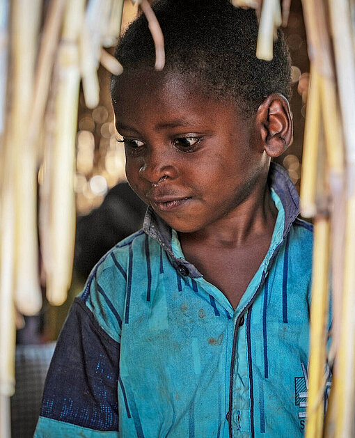 Zu den 8,6 Millionen Kindern, die innerhalb von Sudan auf der Flucht vor dem Krieg sind, zählt auch dieser Junge Ein Junge steht in einer Hütte aus Stroh