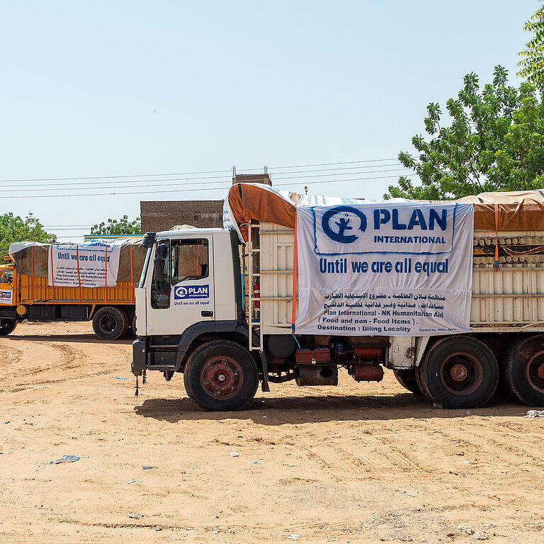 Zwei Trucks mit humanitären Hilfsgütern stehen ein einer trockenen Landschaft