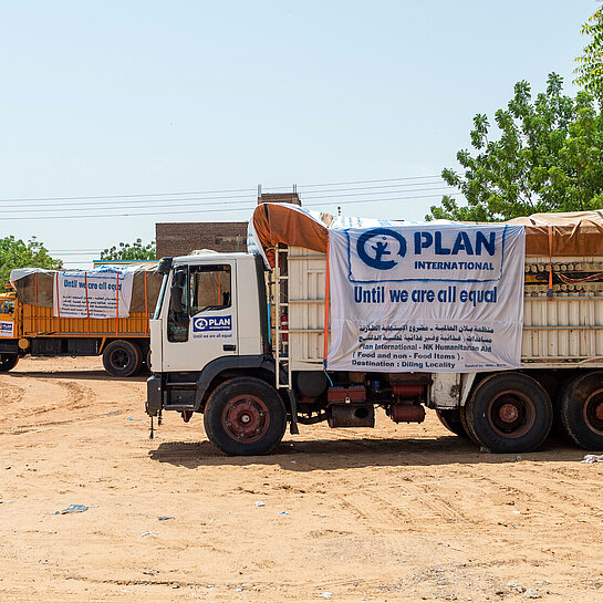 Zwei Trucks mit humanitären Hilfsgütern stehen ein einer trockenen Landschaft