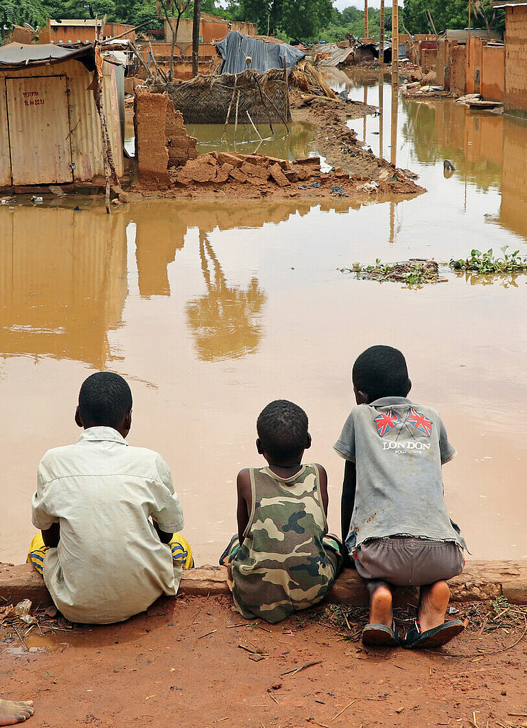 Jungs beobachten ein überschwemmtes Stadtviertel in Niamey, der Hauptstadt Nigers