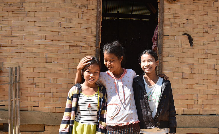 Khai steht mit ihrer Mutter und ihrer Schwester vor ihrem Haus.