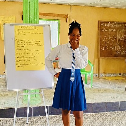 Ein Mädchen steht vor einem Flipchart mit einem selbstgeschrieben Plakat