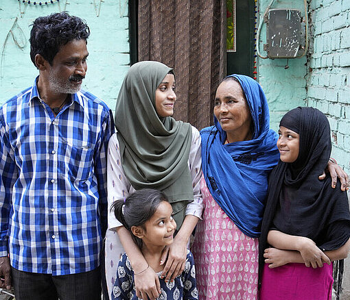 Afsana mit ihren Eltern und zwei ihrer jüngeren Schwestern Eine Familie bestehend aus Vater, Mutter und drei Mädchen steht Arm in Arm zusammen. Alle blicken die älteste Tochter liebevoll an, die in der Mitte steht.