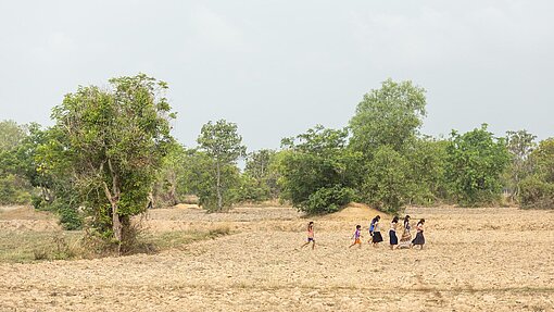 Menschen durchqueren ein trockenes Feld