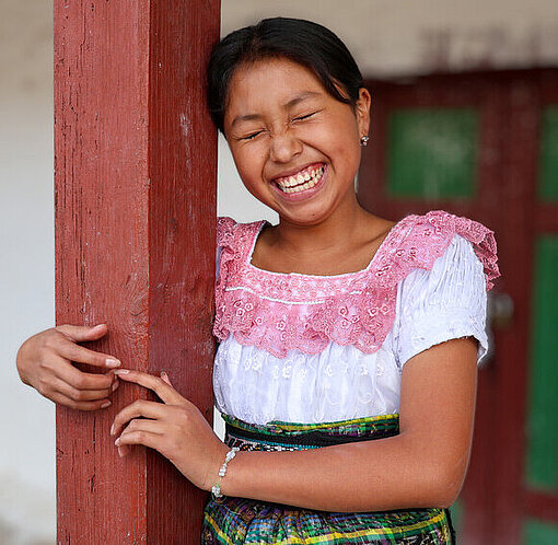 Kimberly lachend neben einem Gebäudepfeiler eines Hauses in Guatemala 