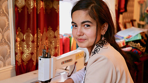 Bibisharifa Talbizoda (18) aus Tadschikistan Bibisharifa arbeitet an Nähmaschine und lacht.