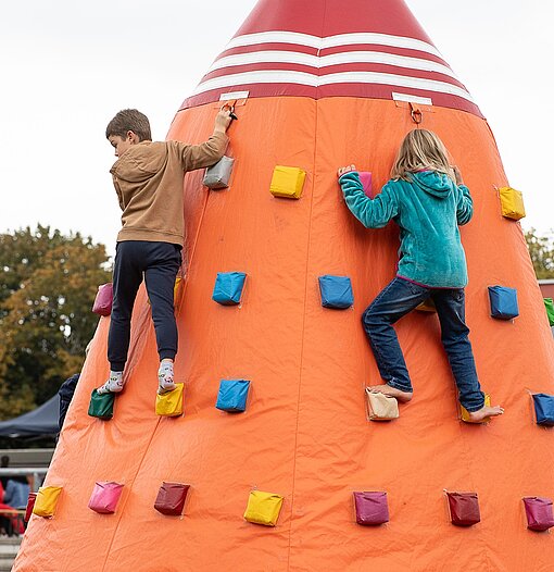 Zwei Kinder klettern einen Kletterturm hoch