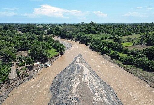 Luftaufnahme von einem Fluss mit bräunlichem Wasser, umgeben von Wald in El Salvador