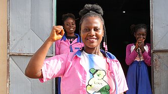 Mädchen in bunten Klamotten reckt selbstbewusst ihre Faust in die Luft