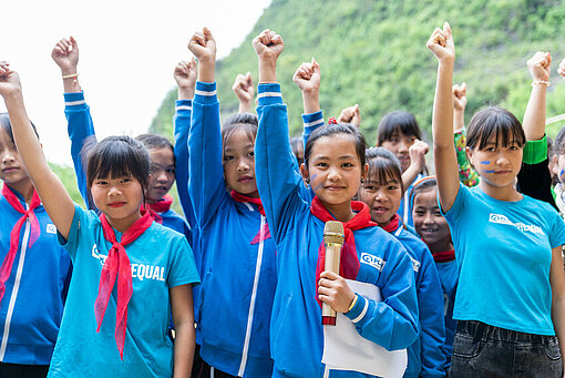 In Vietnam nehmen Mädchen an einem Plan-Workshop teil, der ihnen Führungsfähigkeiten und Selbstvertrauen näherbringt Eine Gruppe Mädchen mit nach oben gestreckten Armen
