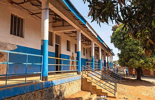 Blick auf ein wei-blau lackiertes Gebäude an einem sandigen Hof