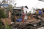 Eine Frau steht in Myanmar in den Trümmern ihres Hauses.